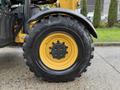 A close-up view of a large black tire with a yellow rim from a 2014 Caterpillar TL1055C forklift showcasing deep treads and bolt patterns