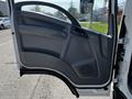 A 2016 Isuzu NPR truck door open showing the interior panel with controls and a speaker grille