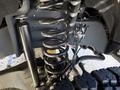 Close-up of the suspension system of a 2024 Ford F-550 showing coil springs and shock absorber components with wiring and other parts visible