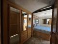 Interior of a 2000 Ford Motorhome featuring wooden cabinetry a bed with a blue mattress and a mirrored wardrobe with multiple drawers