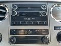 The image shows the dashboard controls of a 2016 Ford F-550 including the radio display climate controls and various buttons for audio settings