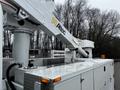 A 2013 International DuraStar bucket truck with an Altec lift system and a metallic service body featuring storage compartments and control panel