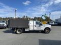 A 2003 Ford F-450 SD with a black cargo box and company markings for junk removal parked on a lot