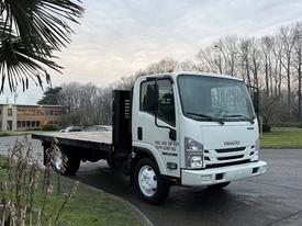 A white 2018 Isuzu NPR truck with a flatbed and side panels facing slightly to the right