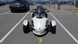 A 2013 Can-Am Spyder with a sleek white body and black accents featuring a distinctive front design and three wheels