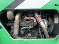Close-up view of the engine of a 2014 JLG 10054 showing various components including pipes and hoses with visible dirt and wear