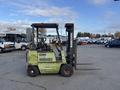 A green 2000 Clark GPS 15 forklift with a black lifting mast and two wooden forks attached at the front