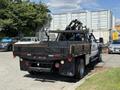 A 2012 Ford F-450 Super Duty with a flatbed and crane attachment in the rear, parked with a simple black bed and various tools secured on it