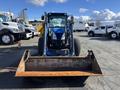 A 2010 New Holland T4050 tractor with a front loader attachment is parked facing forward with large tires and a blue and black color scheme