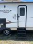 A white 2014 Launch 24RLS travel trailer with a black entrance door and three steps leading up to it featuring a small logo and stickers on the side