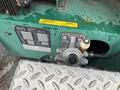 Close-up of a mechanical component featuring a valve and pressure gauge on a green surface with an equipment identification label attached