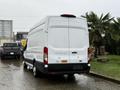 A 2023 Ford Transit van parked with a white exterior and sliding side door viewed from the rear