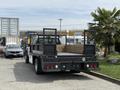 A black 2008 Ford F-550 flatbed truck with a wooden cargo area and visible rear lights parked in a lot