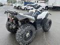 A 2017 Polaris Scrambler ATV with rugged tires and a white and black body design is shown from the rear side. The vehicle features a rear cargo rack and an exhaust pipe.