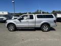 A silver 2014 Ford F-150 parked with a cap on the truck bed and chrome wheels visible from the side