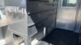 A metal storage unit with multiple drawers is displayed inside a 2013 Ford Econoline vehicle