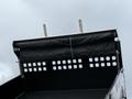 A 2021 Ford F600 truck bed with an open tarp cover featuring a black fabric and metal structure with small ventilation holes