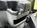 A gray plastic cup holder with a storage compartment below it located in the front section of a 2016 Ford Econoline