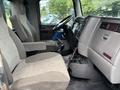 Interior of a 2013 Kenworth T370 showing two gray upholstered seats and the dashboard with control panel and gear shift