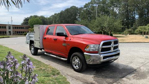 A red 2013 RAM 2500 pickup truck with a silver utility bed and chrome wheels parked on a paved area