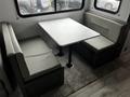 Interior view of a 2022 Aspen Trail with a booth-style dining area featuring a marble tabletop and gray upholstered seating