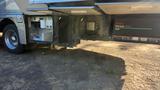 A 2007 Winnebago Adventure motorhome with open storage compartments revealing various equipment and features inside