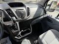 Interior of a 2016 Ford Transit showing gear shifter dashboard controls and seating with a light grey fabric