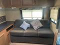 Interior of a 2014 Launch 24RLS featuring a dark sofa with a decorative pillow on it and overhead cabinetry