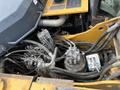 The engine compartment of a 2018 John Deere 350 showing various hydraulic lines pumps and mechanical components