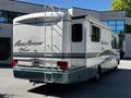 A 2000 Ford Motorhome with a distinct blue and white color scheme featuring the name Pace Arrow Vision on the side and a ladder mounted at the back