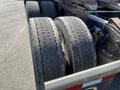 Two worn tires mounted on a Freightliner Cascadia truck's rear axle showcasing visible tread wear and dirt accumulation