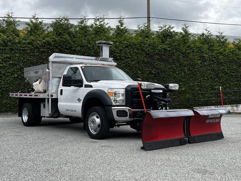 A 2011 Ford F-550 truck equipped with a snow plow attachment in the front and a bed for hauling equipment or materials