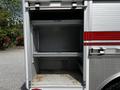 A 2009 Ford F-550 truck with an open storage compartment that has two shelves and an empty interior