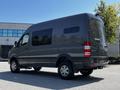 A 2017 Mercedes-Benz Sprinter van in dark gray with large windows and high roof parked at an angle showing its side and rear views