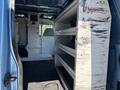 Interior of a 2008 Ford E-350 van featuring metal shelving units on one side and a partition separating the driver area from the cargo space