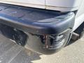 Close-up of the rear bumper of a 2012 GMC Savana showing scratches and scuffs on the black plastic surface