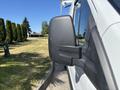 A side mirror of a 2016 Ford Transit van showing a black plastic casing and reflecting trees in the background