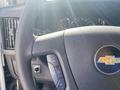 Close-up of the steering wheel and dashboard controls of a 2020 Chevrolet Express featuring the Chevrolet logo and speedometer behind