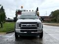 A white 2018 Ford F-550 truck with a utility body and mounted equipment on the roof facing forward
