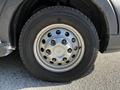 Close-up of a silver wheel with holes and a black tire on a 2023 Ford Transit