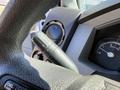 A close-up view of the steering wheel controls in a 2014 Ford F-250 SD showing a turn signal lever and circular dashboard gauge