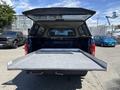 A blue 2015 Ford F-150 with an open truck bed and a fitted cover showcasing a flat surface inside