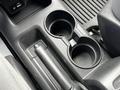 A cup holder console area in a 2020 Nissan NV200 with two circular cup holders and a lever on the side