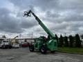 A green 2014 JLG 10054 telescopic handler with a raised fork attachment and large tires parked on a lot