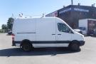 A 2012 Mercedes-Benz Sprinter van in white with a black stripe along the bottom and roof racks on top
