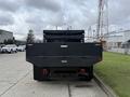 A 2021 Ford F600 truck viewed from the rear with a black dump bed and a tarp covering the load area