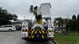 A white 2006 International 7500 bucket truck with a raised aerial work platform and warning stripes on the rear