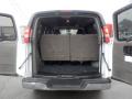 The rear view of a 2011 Chevrolet Express showing the open cargo area with two foldable bench seats in grey upholstery
