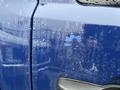A blue 2011 GMC Sierra 3500HD with a rain-soaked surface displaying droplets and a faint reflection on the door