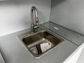 A modern stainless steel sink with a sleek faucet installed in a gray countertop